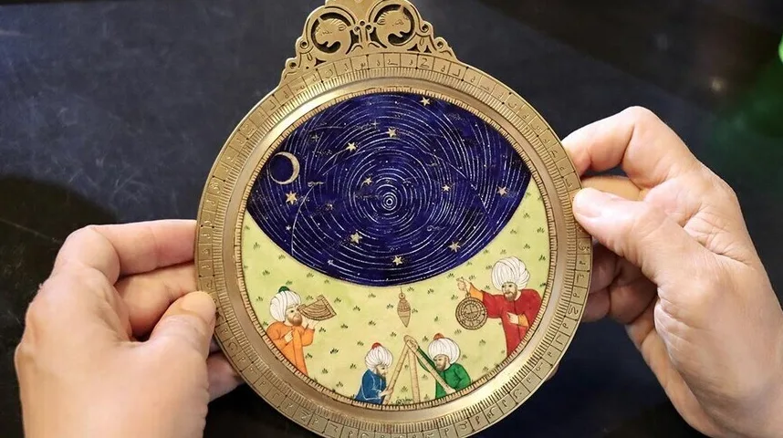 Detalj astrolaba s prikazom zvjezdanog neba i minijaturnih figura ljudi u tradicionalnoj odjeći.