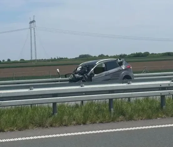 Potpuno smrskani sivi automobil nakon teške saobraćajne nesreće na autoputu.