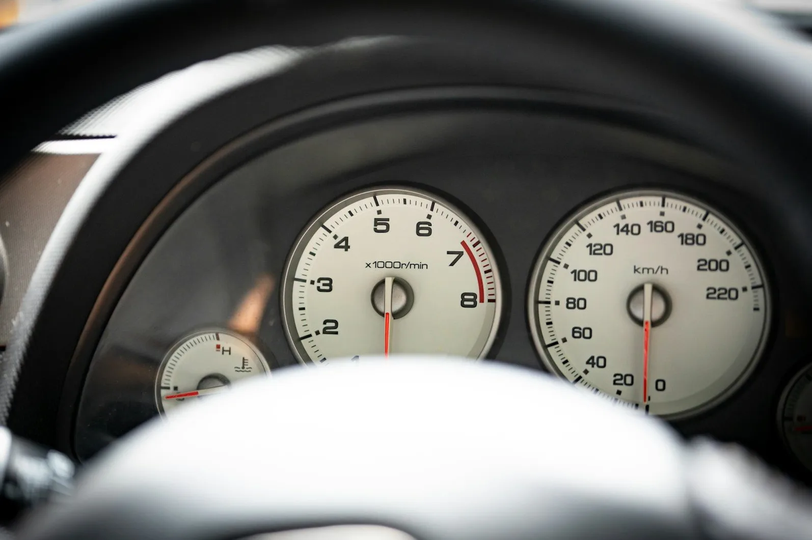 Detaljan pogled na instrument tablu automobila, sa fokusom na brzinomjer i brojač obrtaja motora.