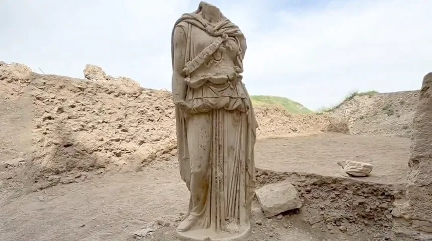 Odrezana kamena statua u arheološkom nalazištu.