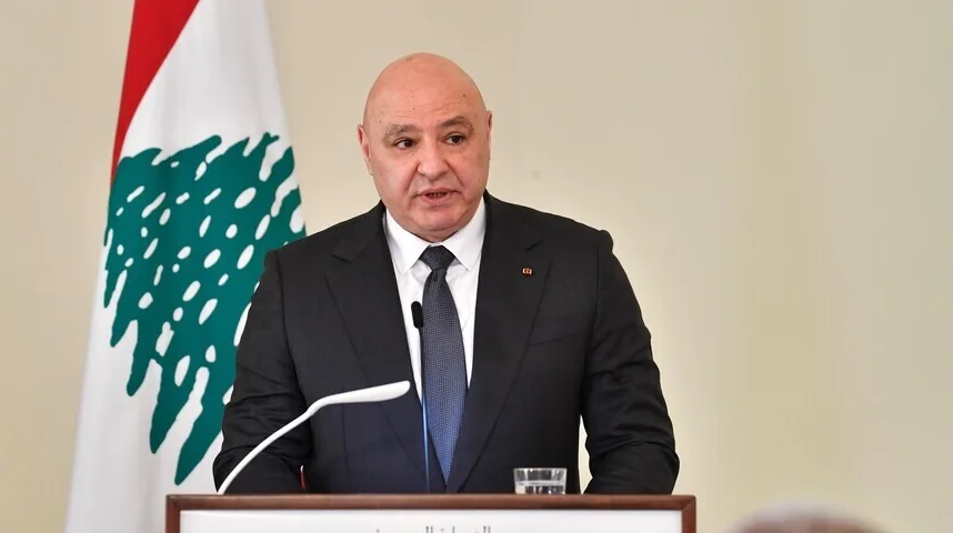 Libanski političar u crnom odijelu i plavoj kravati govori za govornicom, sa zastavom Libana u pozadini.