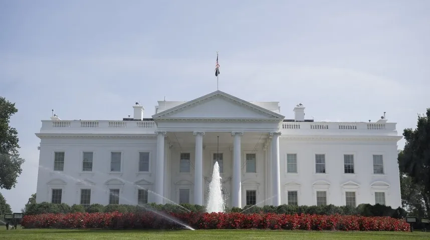 Bijela kuća sa fontanom i crvenim cvijećem u prvom planu