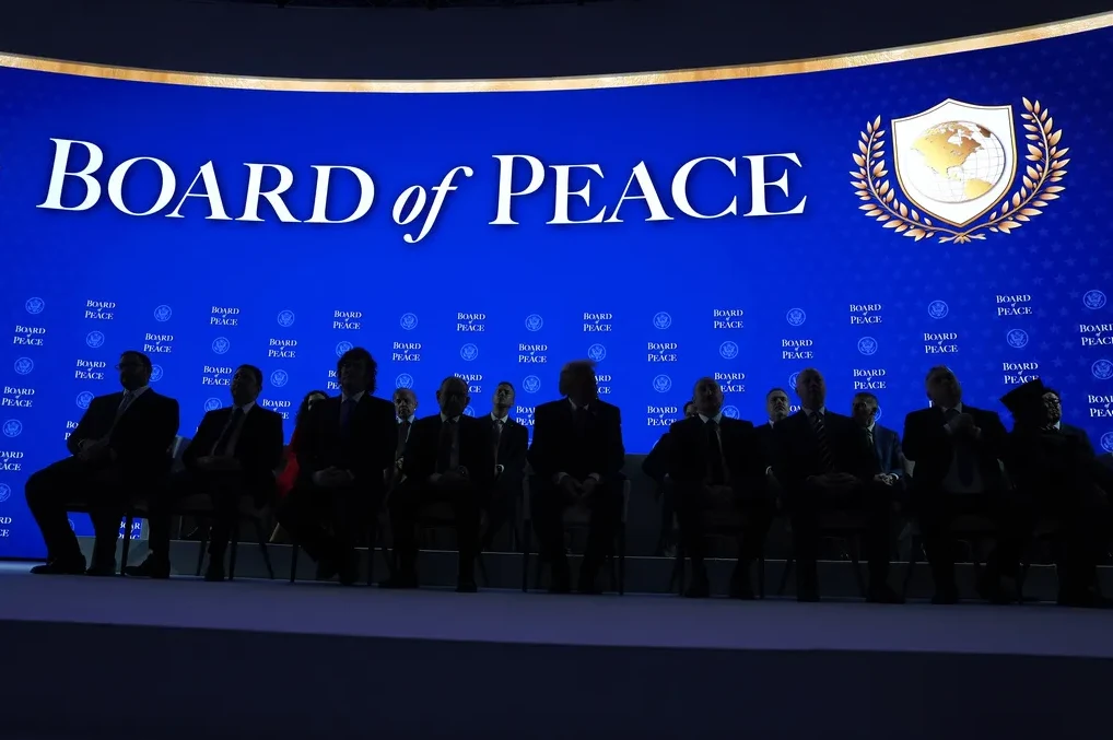 Grupa muškaraca u odijelima sjedi ispred plave pozadine s natpisom "BOARD of PEACE" i grbom.
