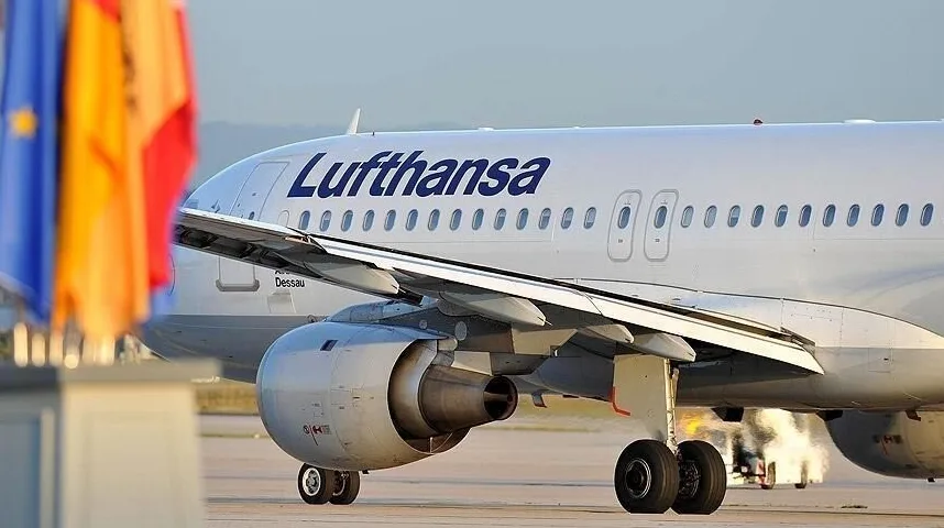 Avion kompanije Lufthansa na pisti, sa zastavama u prvom planu.