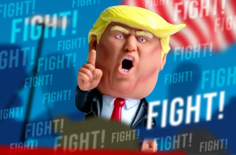 Figurica Donalda Trampa sa podignutim kažiprstom i otvorenim ustima, sa pozadinom koja prikazuje riječ "BORBA!" više puta.