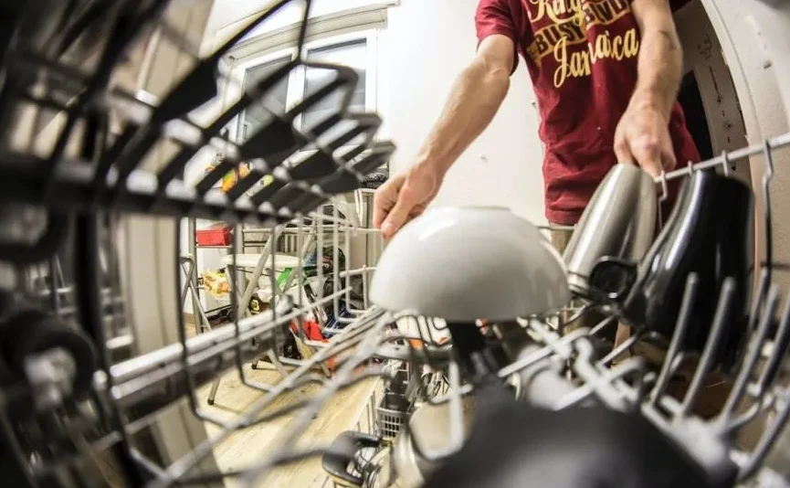 Čovjek slaže suđe u mašinu za pranje suđa, uključujući šolje i zdjelu
