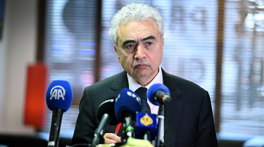 Čovjek sa sijedom kosom u tamnom odijelu stoji ispred više mikrofona, od kojih jedan nosi logo AA.