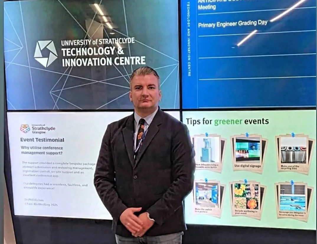 Muškarac pozira ispred ekrana sa logom i nazivom „University of Strathclyde, Technology & Innovation Centre“.