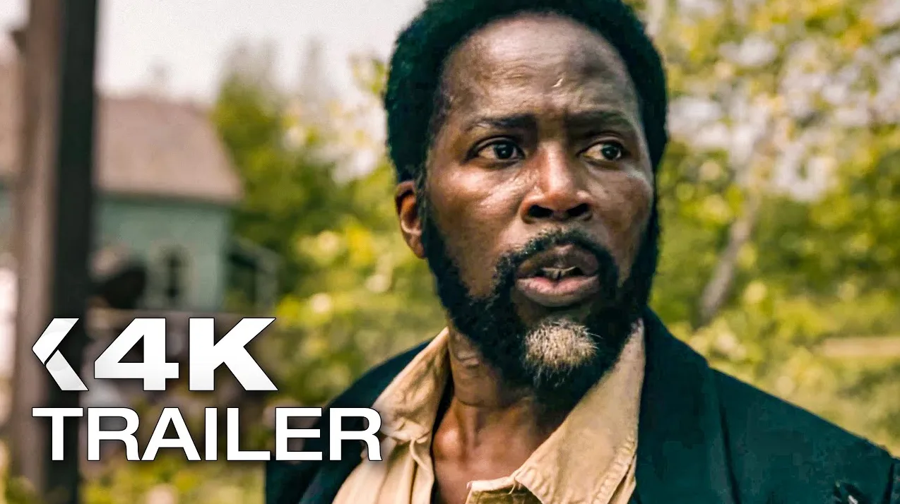 Crnac sa bradom i raščupanom kosom, u prljavoj košulji i crnom sakou, uplašenog izraza lica, s natpisom "4K TRAILER" ispred sebe.