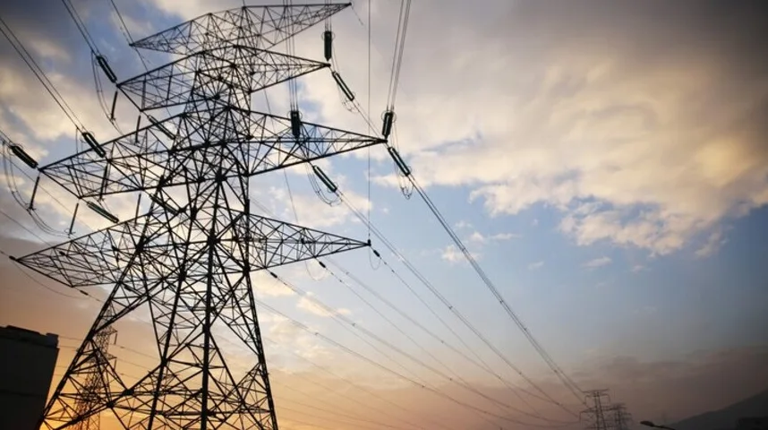 Visoki dalekovod sa električnim žicama pod zalaskom sunca.