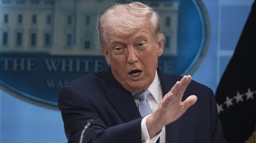 Donald Tramp, bivši američki predsjednik, drži ruku u gestikulaciji dok govori ispred znaka Bijele kuće.