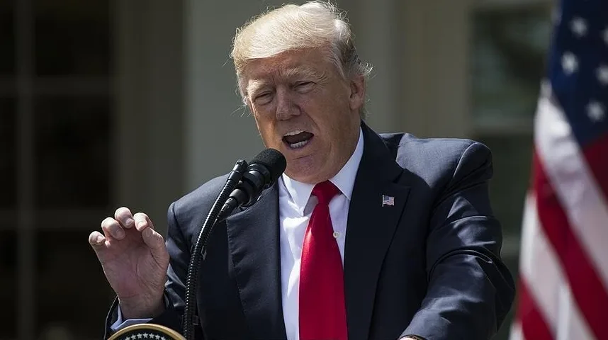 Donald Trump sa rukom podignutom, govoreći u mikrofon.