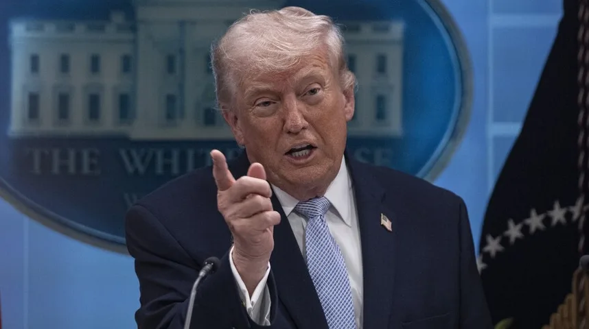 Donald Trump, bivši američki predsjednik, obraća se javnosti s podignutim kažiprstom ispred podloge sa logom Bijele kuće.