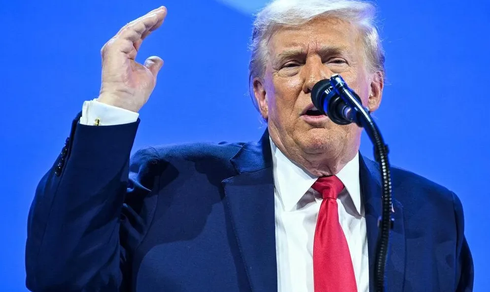 Donald Trump podiže ruku dok govori za mikrofonom