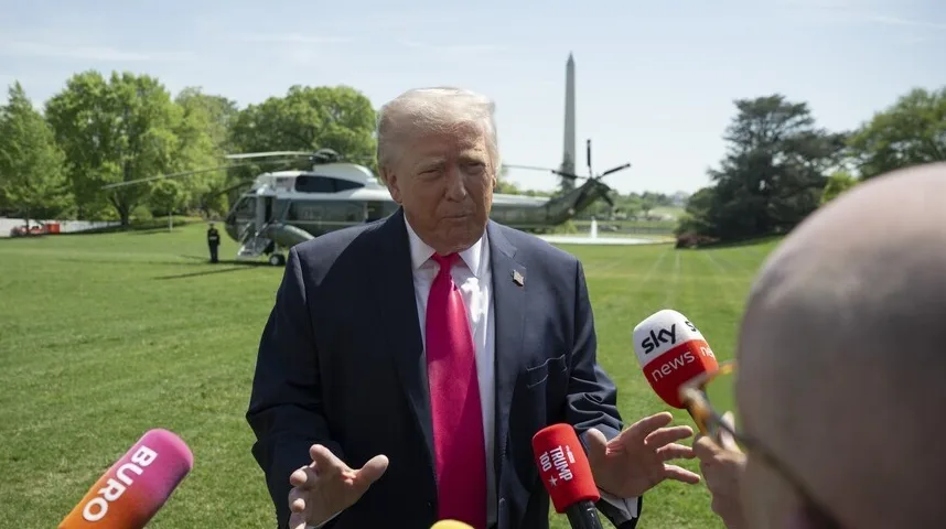 Donald Trump u tamnom odijelu i crvenoj kravati daje izjavu novinarima ispred Bijele kuće.