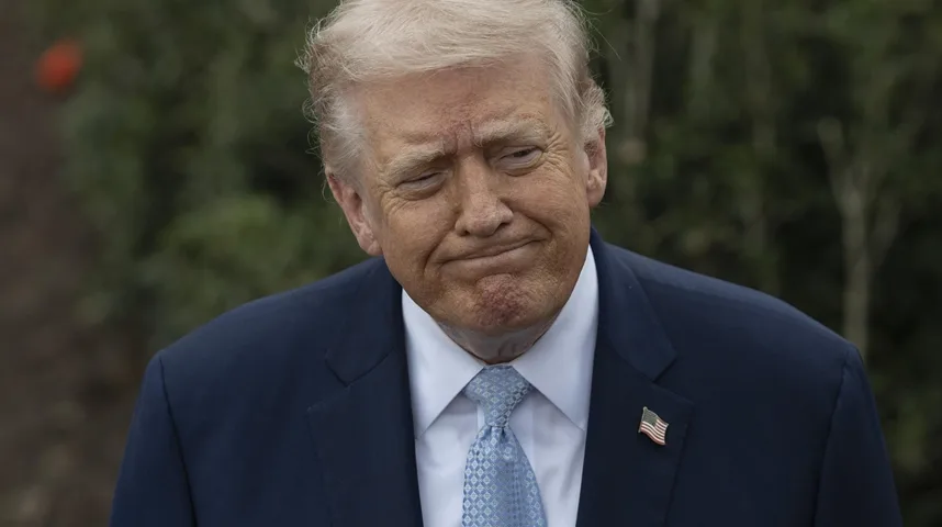 Detaljan kadar bivšeg američkog predsjednika Donalda Trumpa u tamnoplavom odijelu i plavoj kravati s uzorkom, s blagim namrštenim izrazom lica.