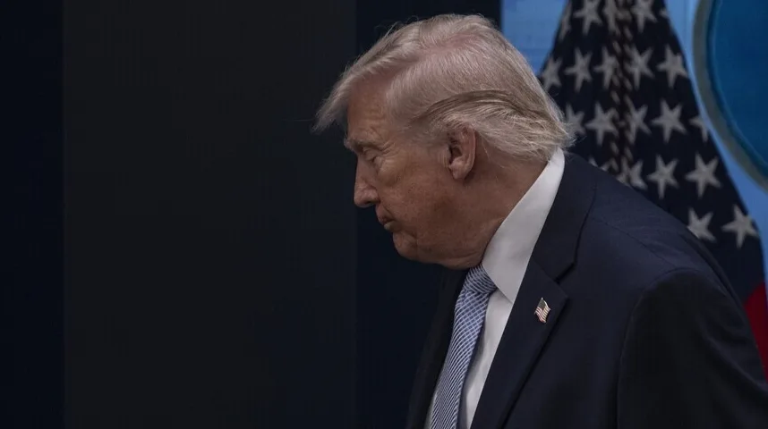 Donald Trump gleda prema dolje s američkom zastavom u pozadini.