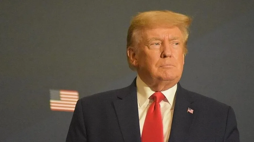 Donald Trump u tamnom odijelu i crvenoj kravati gleda udesno.