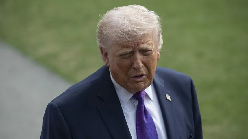 Donald Trump u tamnoplavom odijelu i ljubičastoj kravati gleda prema dole.