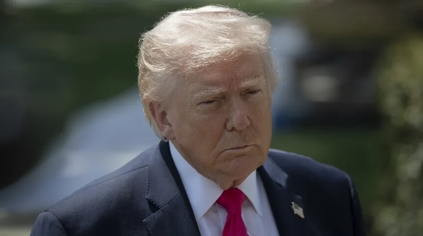 Portret bivšeg američkog predsjednika Donalda Trumpa u tamnom odijelu i košulji s ružičastom kravatom, sa lijepo oblikovanom plavom kosom i ozbiljnim izrazom lica.