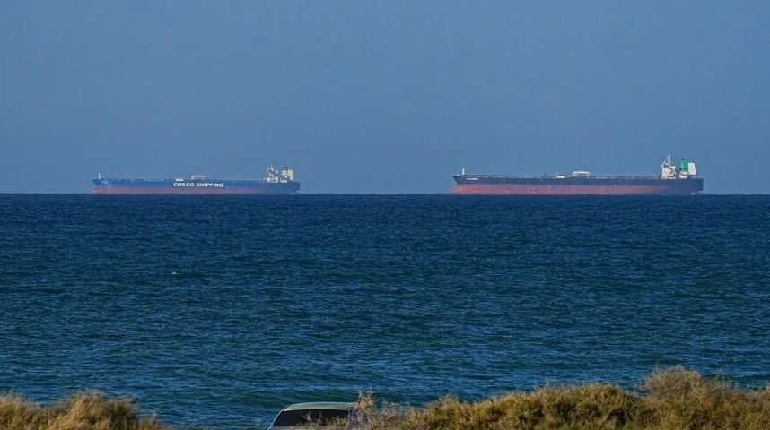 Dva velika teretna broda plove mirnim plavim morem pod vedrim nebom.