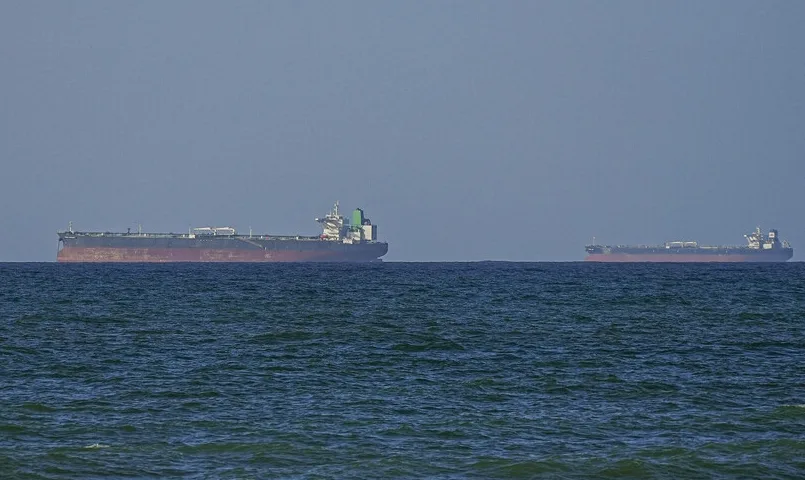 Dva velika teretna broda plove preko mirnog mora pod vedrim nebom.