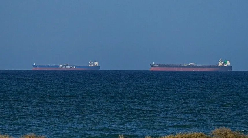 Dva velika teretna broda plove mirnim morskim plavetnilom pod jasnim plavim nebom.