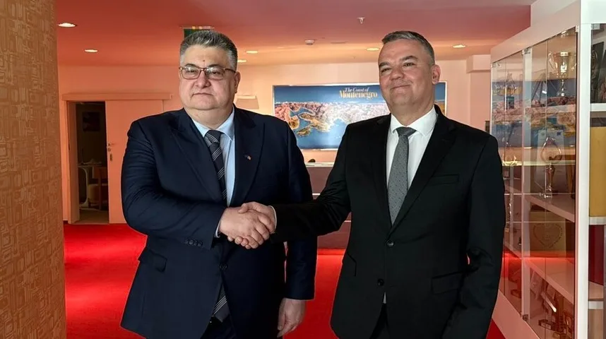 Dva muškarca u odijelima rukuju se ispred mape Crne Gore.