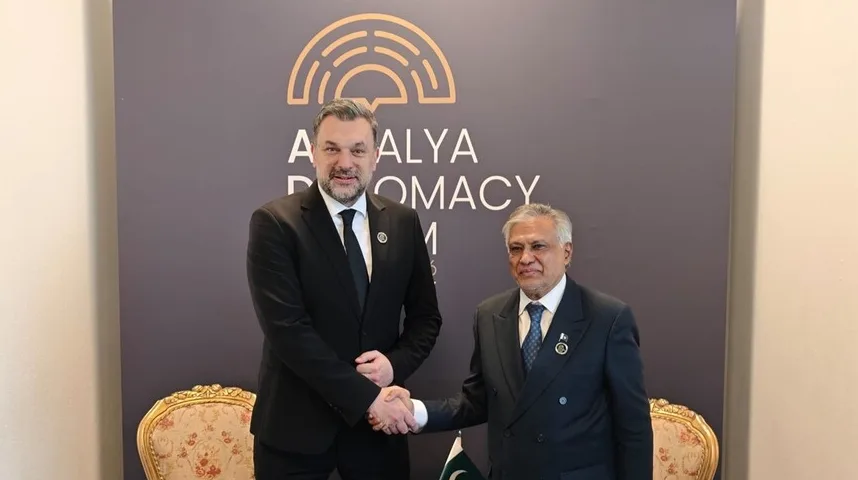 Dvojica muškaraca u svečanim odijelima rukuju se ispred pozadine s logotipom Antalya Diplomacy Forum.