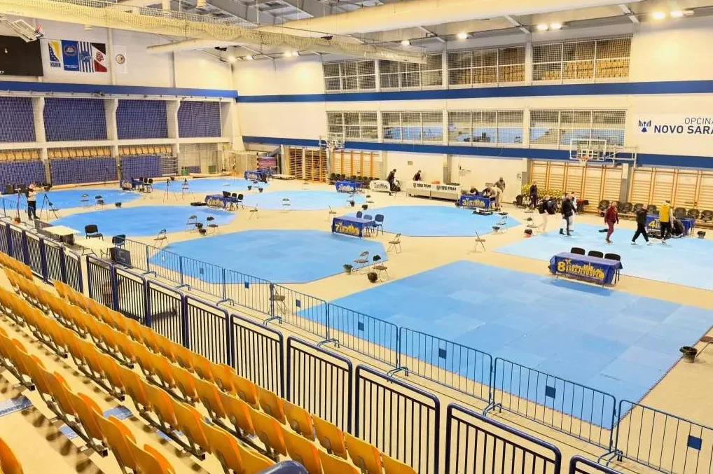 Unutrašnjost dvorane sa postavljenim plavim tatamijem i stolovima sa strane