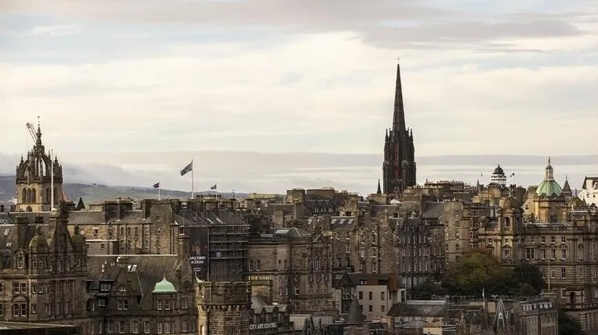 Panoramski pogled na arhitekturu Edinburga sa oštrim zvonikom i tradicionalnim zgradama.