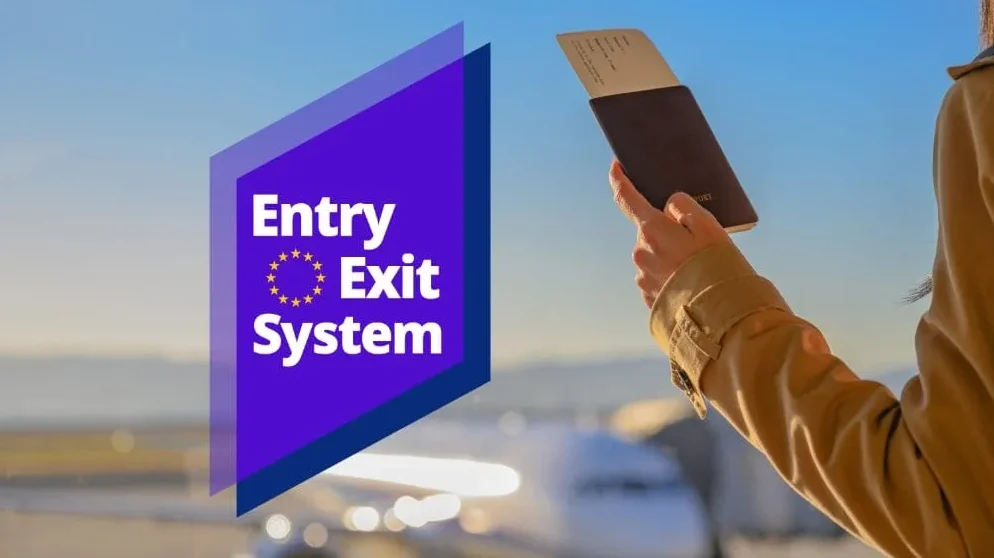 Osoba drži pasoš ispred aviona na aerodromu, sa logom "Entry Exit System" EU.