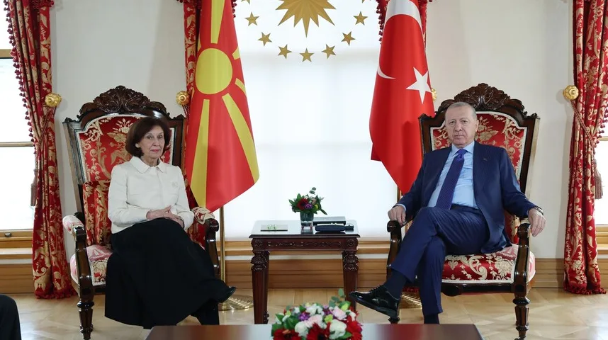 Recep Tayyip Erdoğan i predstavnica Sjeverne Makedonije sjede u foteljama, sa zastavama Turske i Sjeverne Makedonije u pozadini.