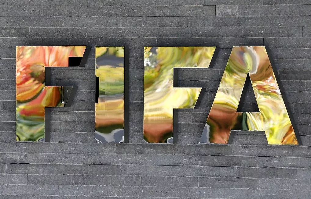 Slovo 'FIFA' ispisano velikim, sjajnim metalnim slovima na tamnoj, kamenoj pozadini.