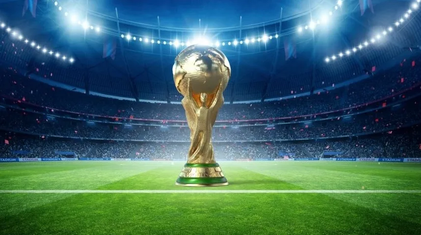 Zlatni trofej Svjetskog prvenstva u fudbalu postavljen na zelenom terenu stadiona, osvijetljen reflektorima pred punim gledalištem.