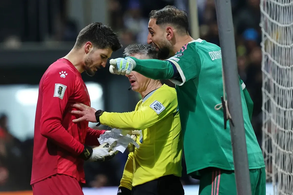 Dva fudbalska golmana i sudija razgovaraju na terenu.