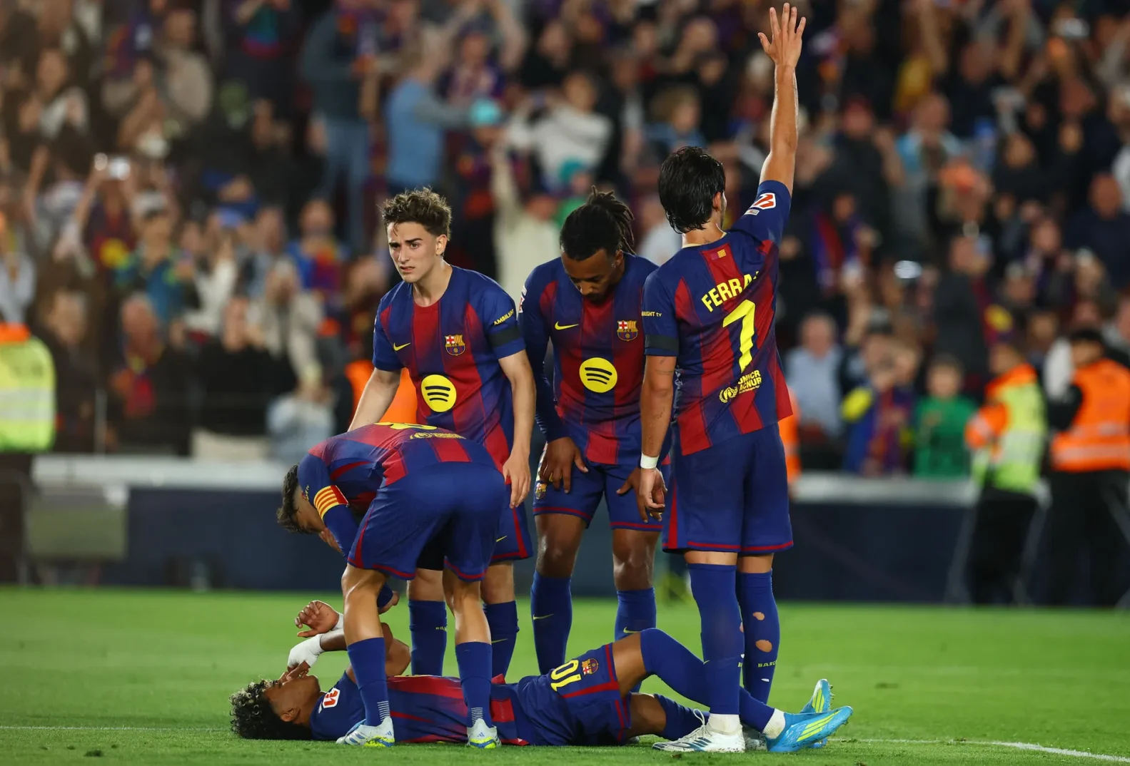 Fudbaler Barcelone, Gavi, leži na travnjaku dok ga njegovi suigrači, uključujući Ferrana Torresa, zabrinuto promatraju.
