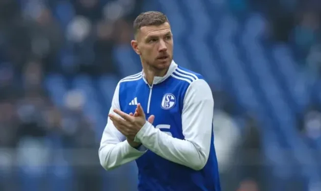 Fudbaler u plavom dresu Schalkea sa bijelim rukavima aplaudira.