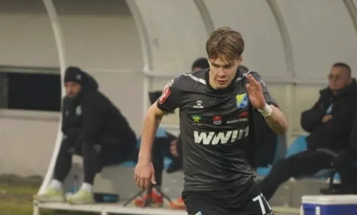 Fudbaler u crnom dresu sa brojem 71 na leđima, u pokretu na terenu.