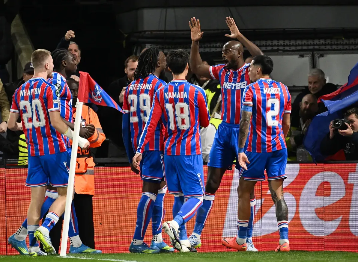 Fudbaleri Kristal Palasa u dresovima sa brojevima 20, 29, 18 i 2 slave gol na terenu. Jedan od njih podiže ruke u zrak dok ga ostali grle.