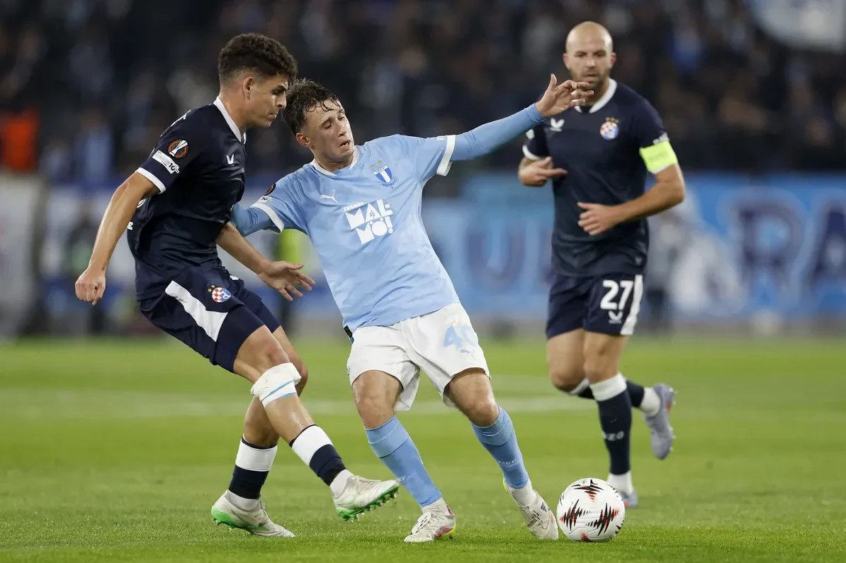 Dva fudbalera se bore za loptu na terenu.