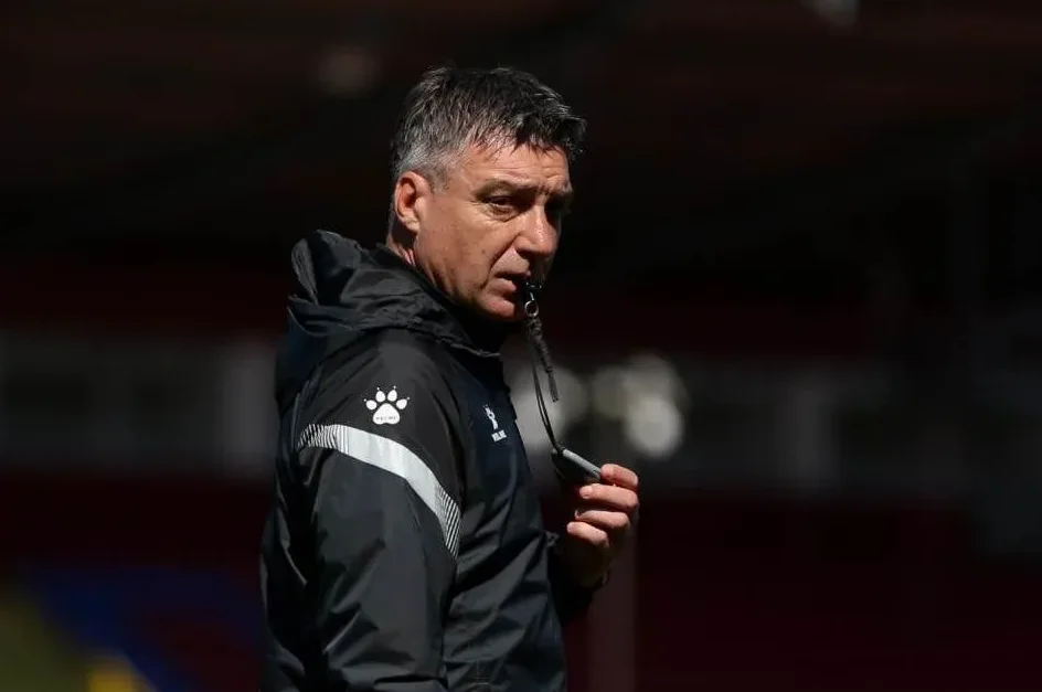 Fudbalski trener drži sviralu u ruci i gleda prema naprijed.