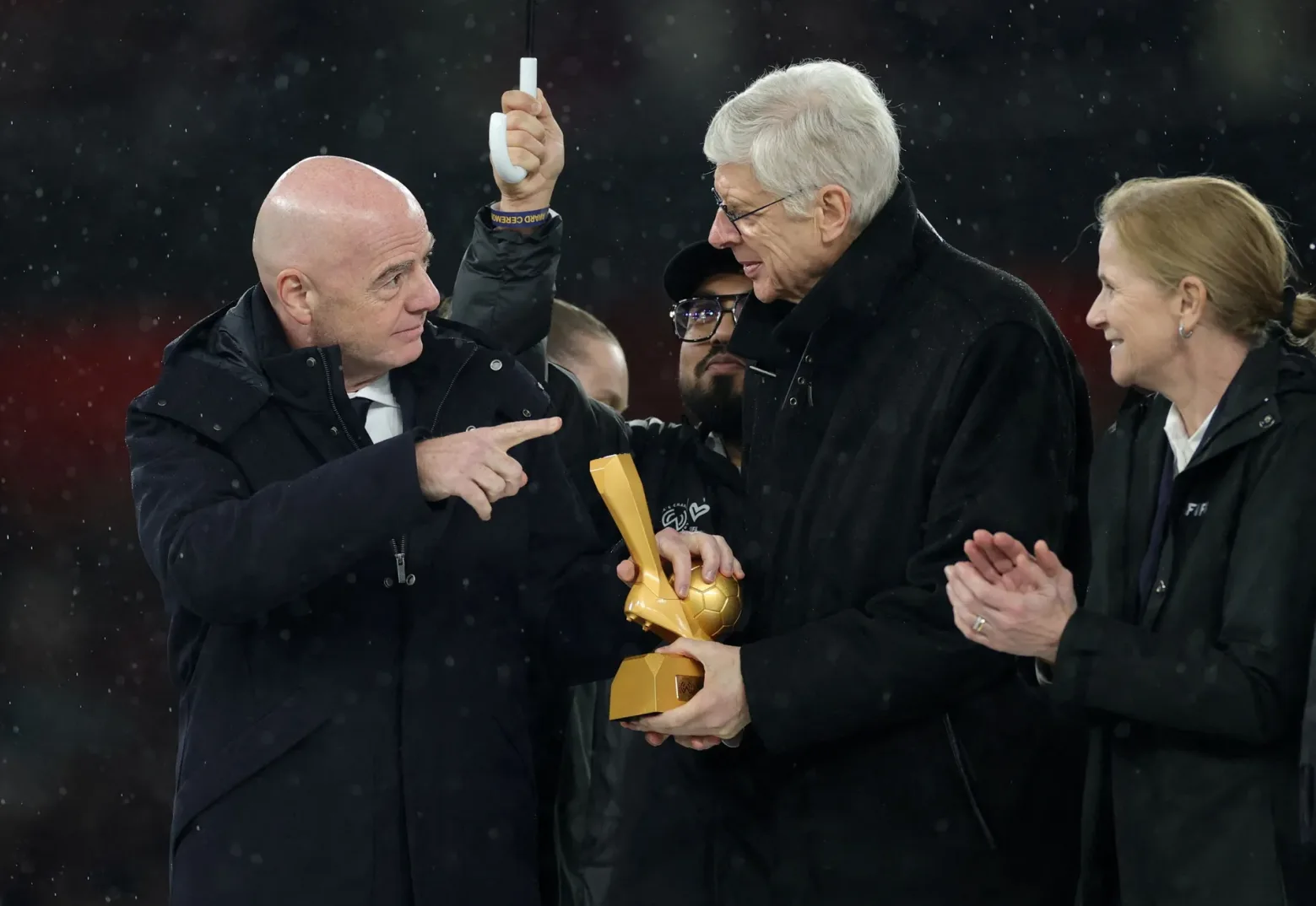 Đani Infantino i Arsene Wenger dijele zlatni fudbalski trofej dok pada kiša.