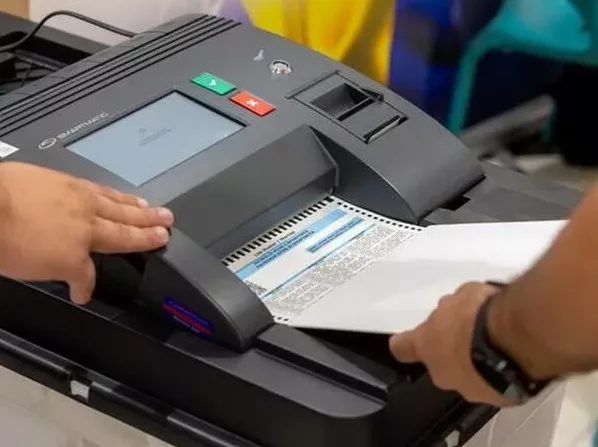 Čovjek ubacuje glasački listić u Smartmatic mašinu