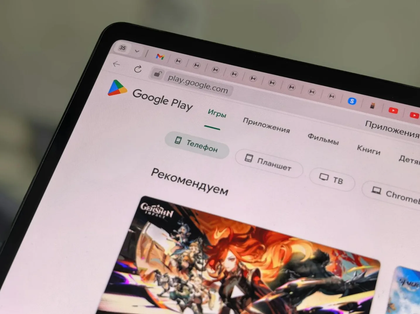 Ekran tableta sa otvorenim Google Play Store-om, prikazuje naslovnu stranu sa igrom Genshin Impact i kategorijama kao što su "Igre", "Aplikacije" i "Preporučujem".