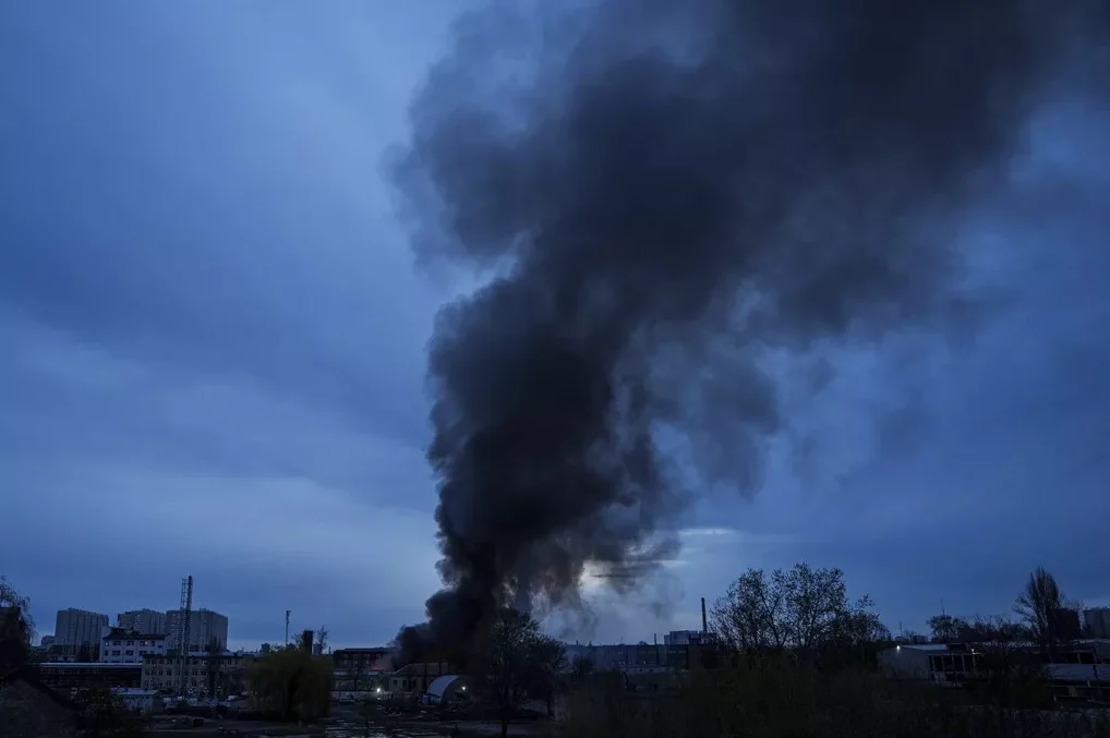 Crni dim sa požara diže se iznad industrijske zone u sumrak.