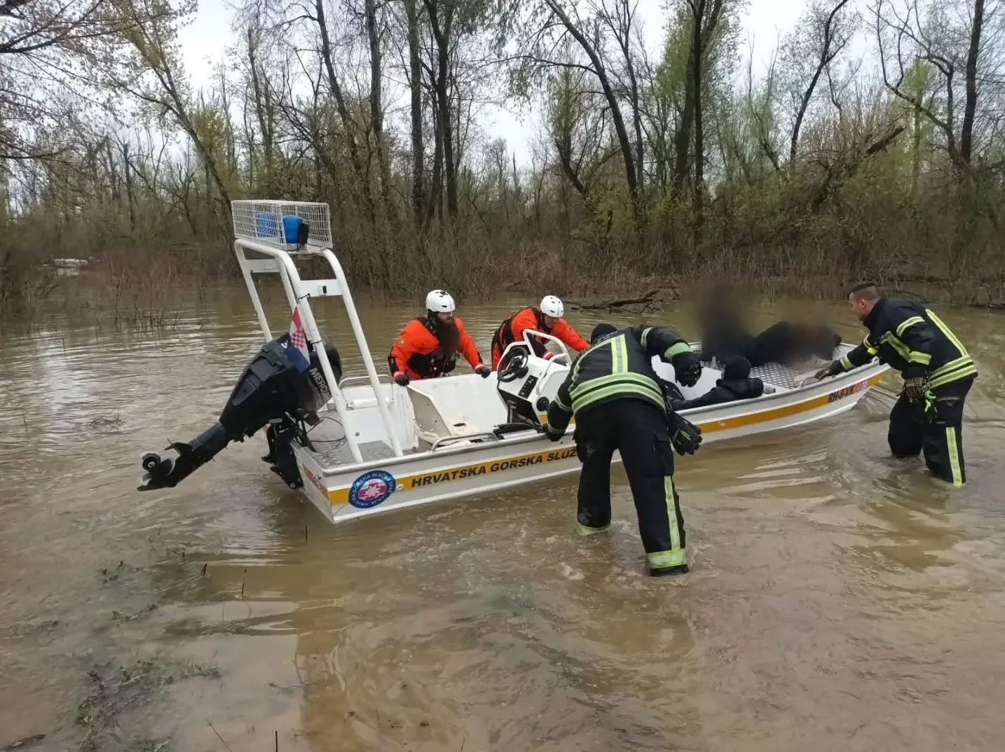 Članovi Hrvatske gorske službe spašavanja u čamcu na poplavljenom području pomažu osobi.