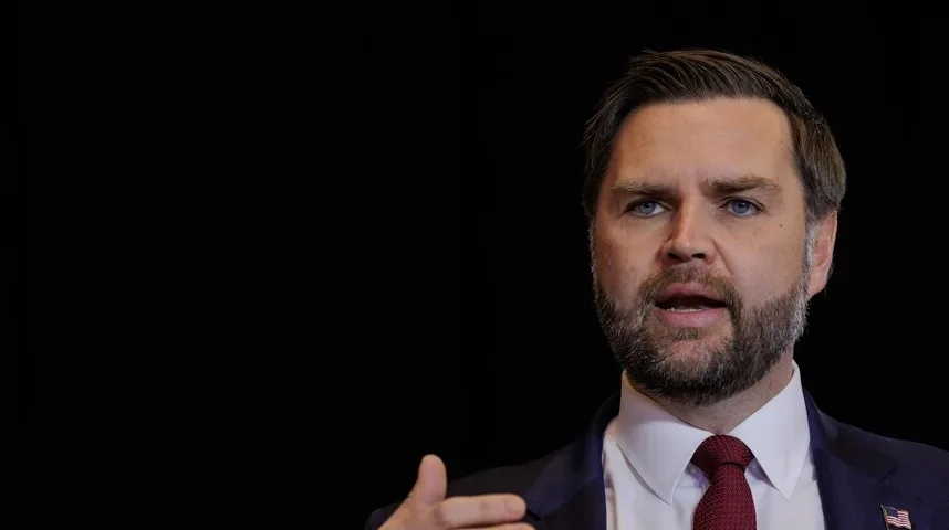 Čovjek s plavim očima, bradom i tamnim odijelom govori