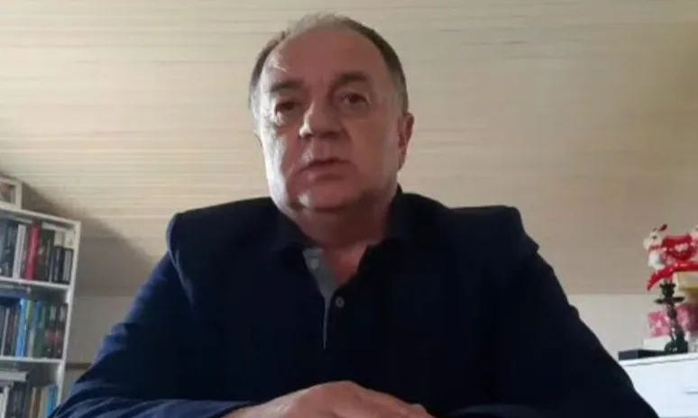 Portret muškarca srednje dobi u tamnoplavom odijelu.