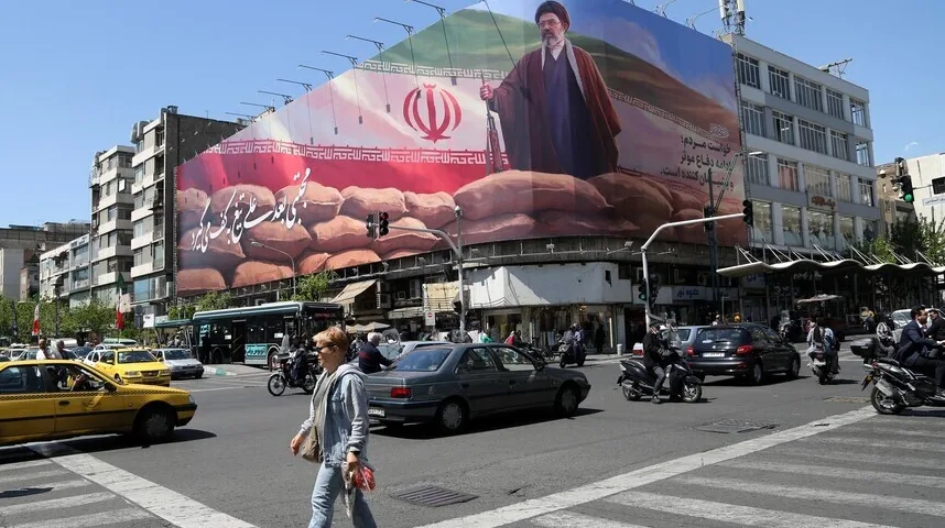 Veliki bilbord sa likom ajatolaha Homeinija i iranskom zastavom iznad vreća pijeska, na prometnoj gradskoj raskrsnici u Iranu.